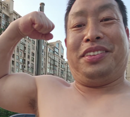 Lee Vin Green smiling and flexing his arm outdoors